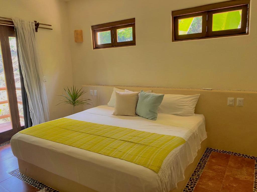 1 dormitorio con 1 cama grande con manta amarilla en A Son de Mar - Playa Las Gatas acceso por mar en Zihuatanejo