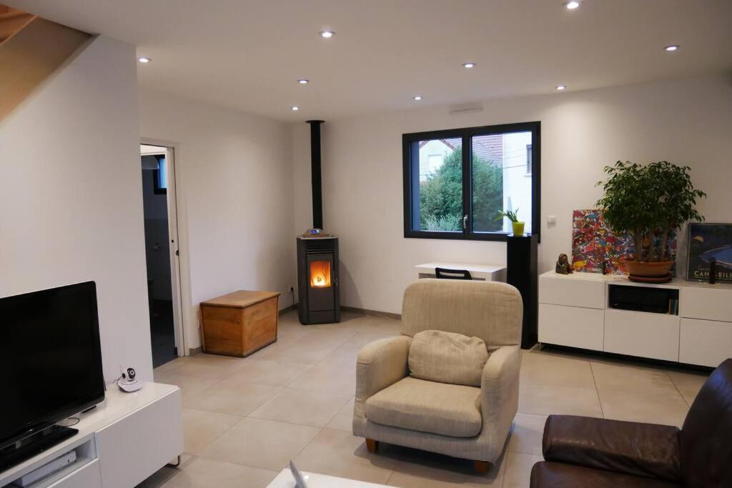 ein Wohnzimmer mit einem TV, einem Sofa und einem Stuhl in der Unterkunft Maison moderne proche de Paris in Montigny-lès-Cormeilles
