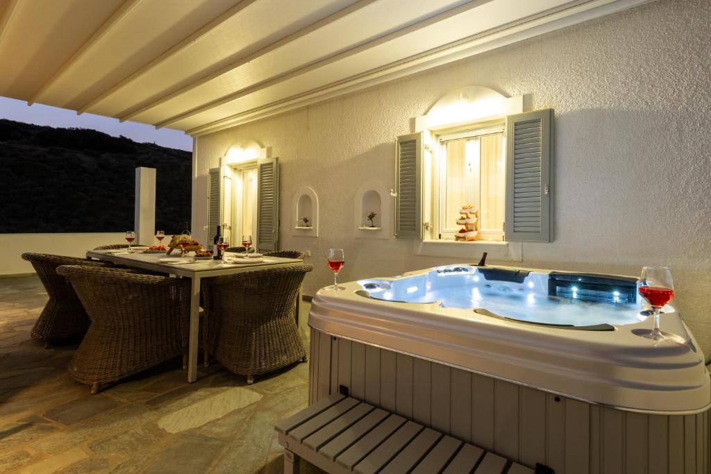 a hot tub in a room with a table and two glasses of wine at Panos Villa Asteras in Isterni