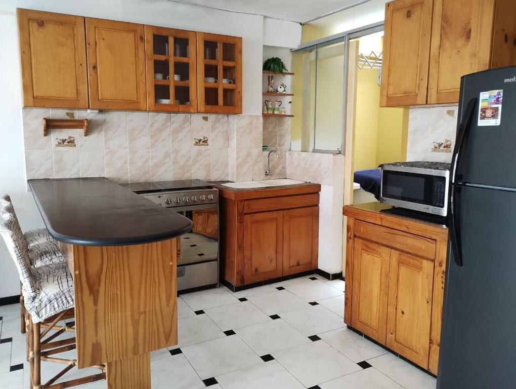 eine Küche mit Holzschränken und einem schwarzen Kühlschrank in der Unterkunft Acogedor Departamento en la Playa in Punta Hermosa
