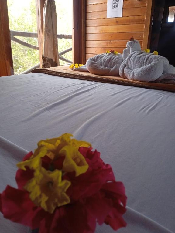 a bed with white towels and a flower on it at El Pajas in Puerto Velasco Ibarra