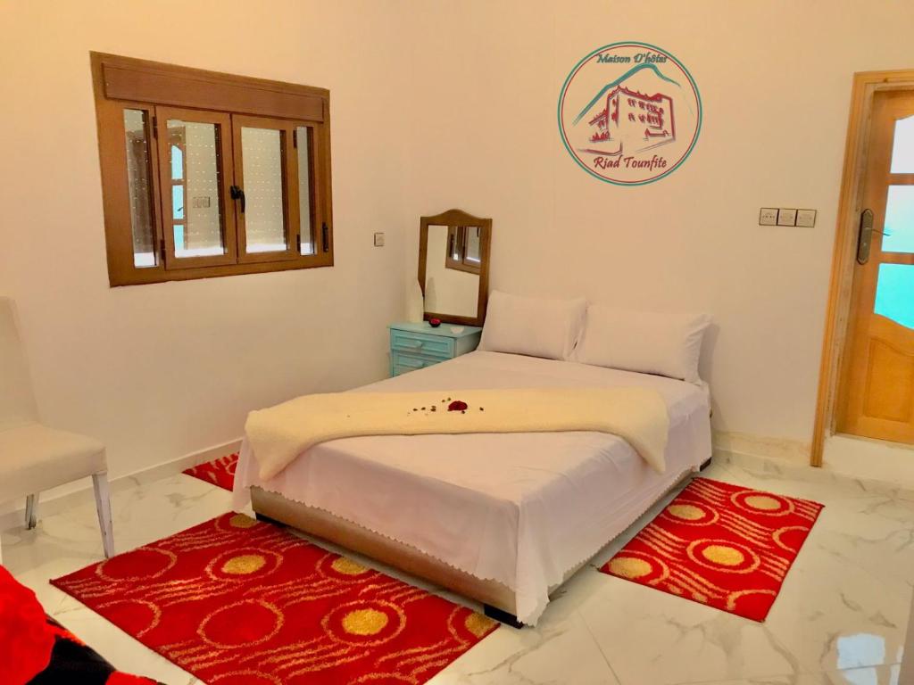 una camera da letto con un letto e uno specchio a parete di Maison d'hôte Riad Tounfite 