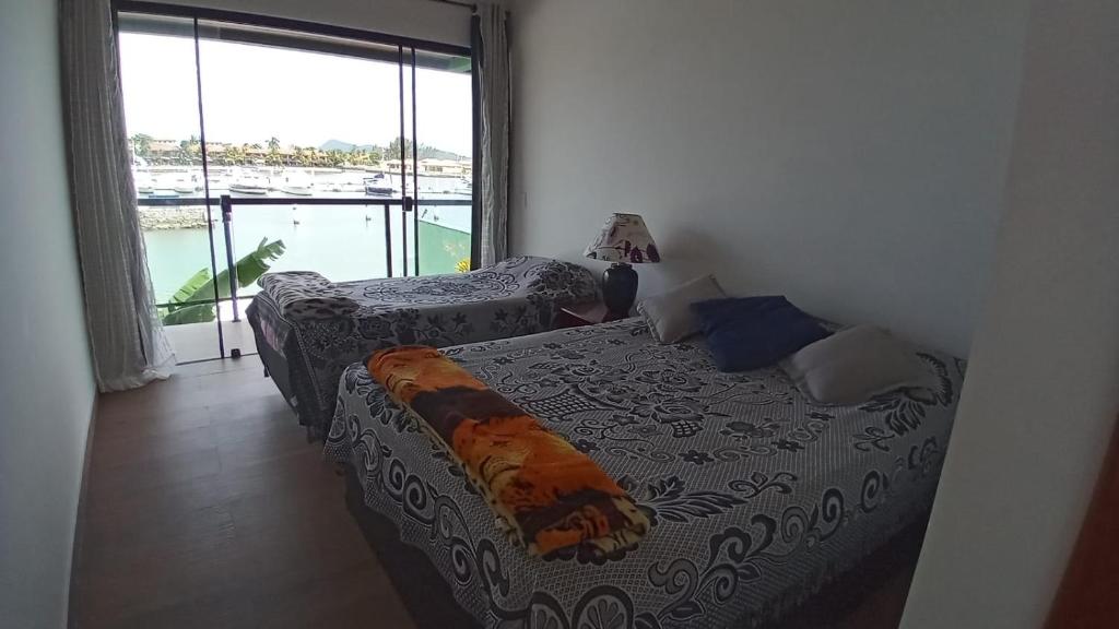 a bedroom with two beds and a large window at Morada do Canal Suites em Búzios in Búzios