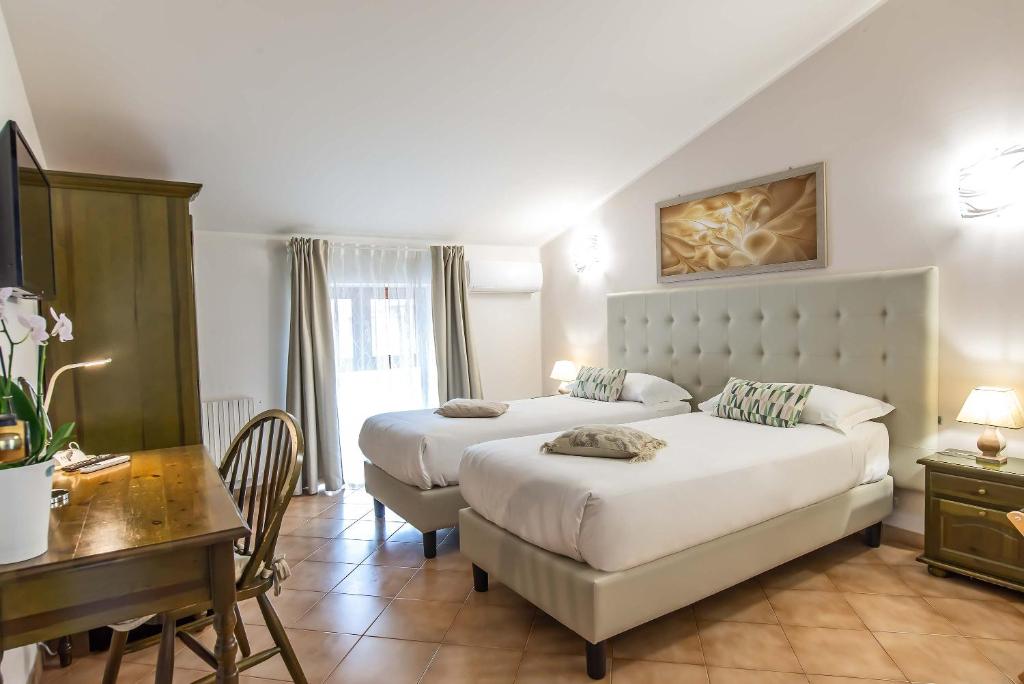 a bedroom with two beds and a table and a desk at Plaza Rooms Ciampino in Ciampino