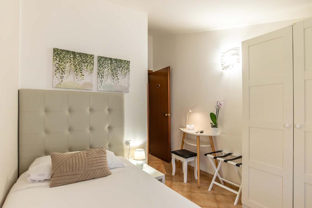 a bedroom with a white bed and a table at Plaza Rooms Ciampino in Ciampino