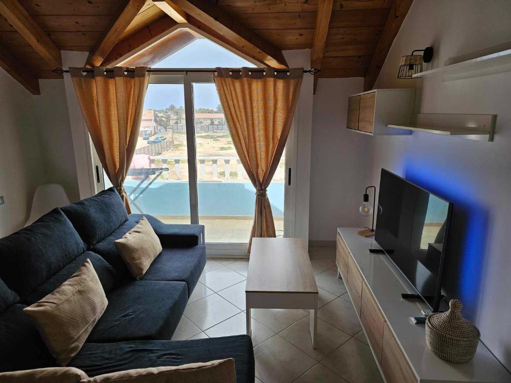 a living room with a blue couch and a tv at Soleil Beach House in Santa Maria