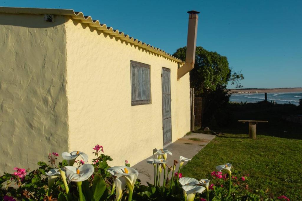 una pequeña casa con flores en el patio en Casa Binah, en Cabo Polonio