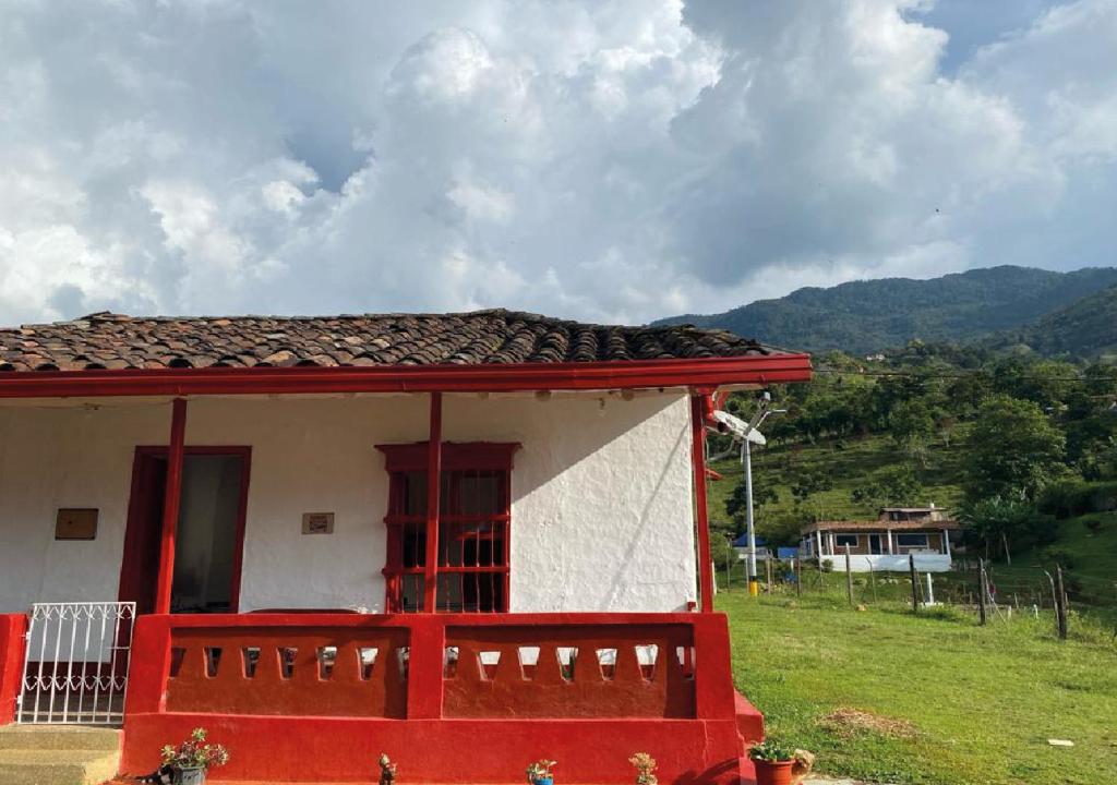 una casa roja y blanca con una montaña en el fondo en Habitación Caoba, en Girardota