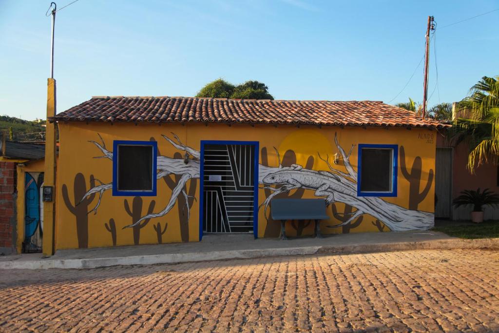un edificio amarillo con una pintura de un árbol en él en Calango Hostel, en Ibicoara