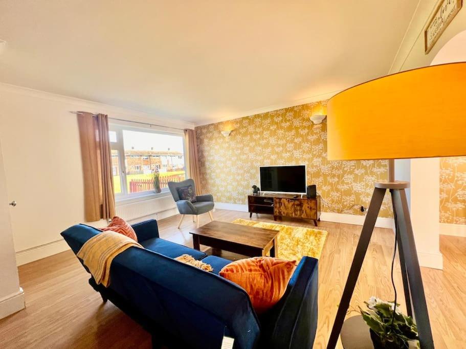 a living room with a blue couch and a television at Canvey Island Bliss By Artisan Stays I Weekly & Monthly Stay Offer I Free Parking in Canvey Island