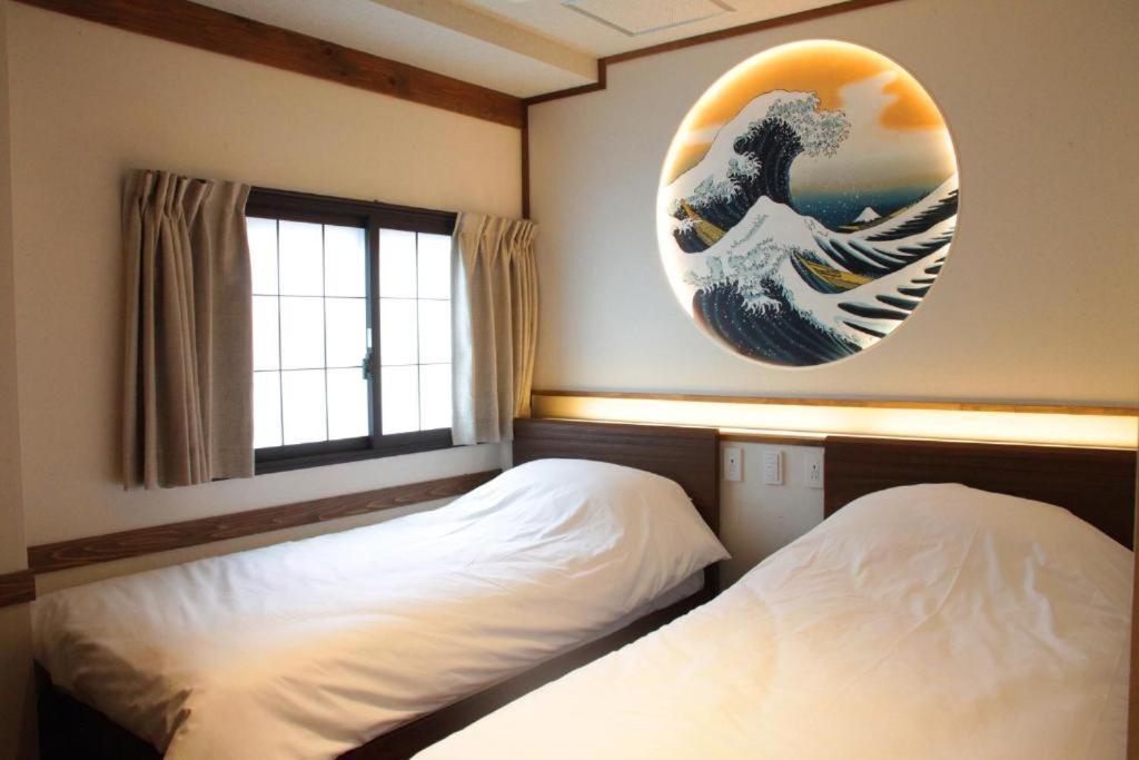 a bedroom with two beds and a painting of a wave at 【都電屋203】标准间/都电荒川线/近三ノ輪/一线直达秋叶原/上野/浅草 in Tokyo