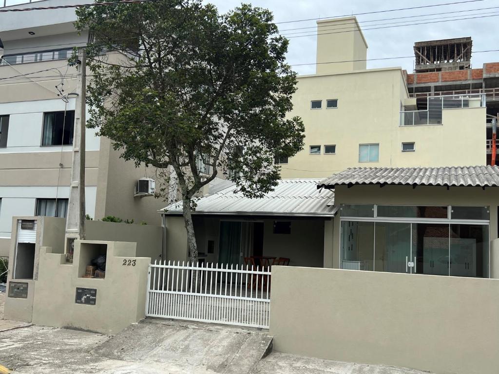 una casa con una valla blanca delante de un edificio en Casa entre dois mares - Casa Bege, en Bombinhas