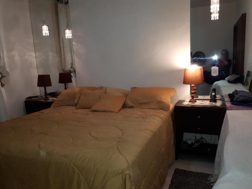 a bedroom with a bed and two tables and a lamp at Chacara Salmo 27 in Antonina