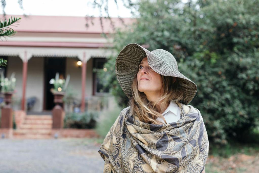 a woman wearing a hat standing in front of a house at Summerlands - Country Luxe in Alexandra