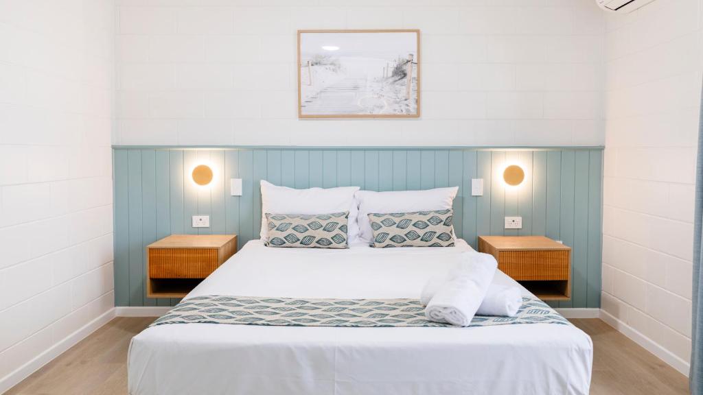 sypialnia z dużym białym łóżkiem z dwoma stołami w obiekcie Palm View Holiday Apartments w mieście Bowen