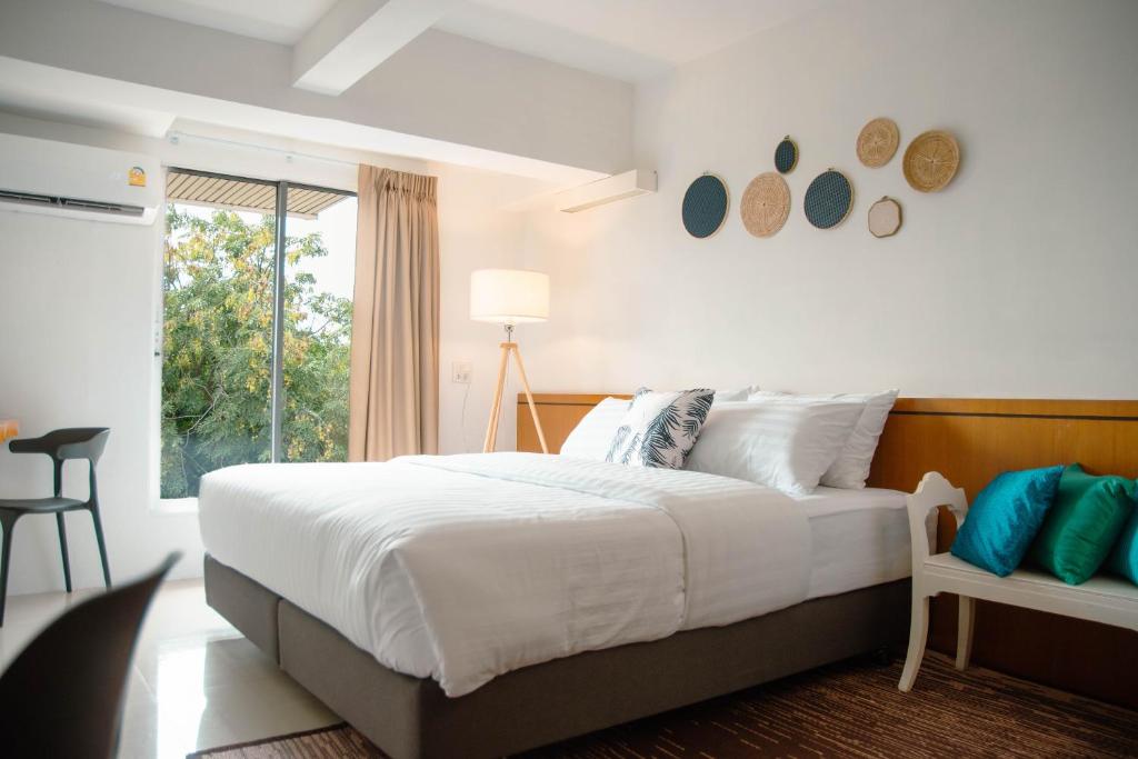 a bedroom with a large white bed and a window at Alley & Pier in Bangkok