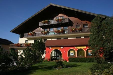 ein großes rotes Gebäude mit Balkonen darüber in der Unterkunft Pension Edelweiss in Sankt Martin am Tennengebirge