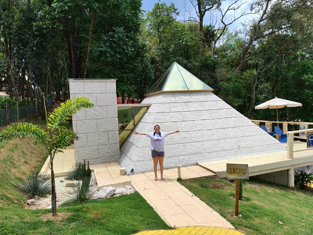 une femme debout devant un bâtiment en forme de pyramide dans l'établissement Pirâmide Quéops, Vila Mágica, à Bueno Brandão