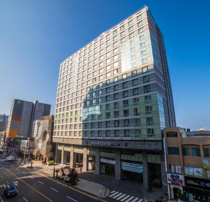 un edificio alto de cristal en una calle de la ciudad en J-Grand Hotel en Jeju