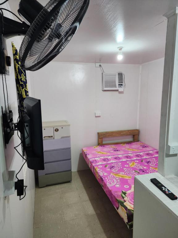 um pequeno quarto com uma cama e uma televisão em GoodWorks Accommodation em Yangor