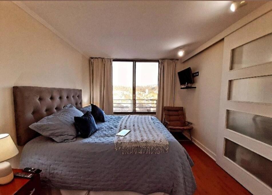 um quarto com uma cama grande e uma janela em dpto pleno centro turístico de viña del mar em Viña del Mar