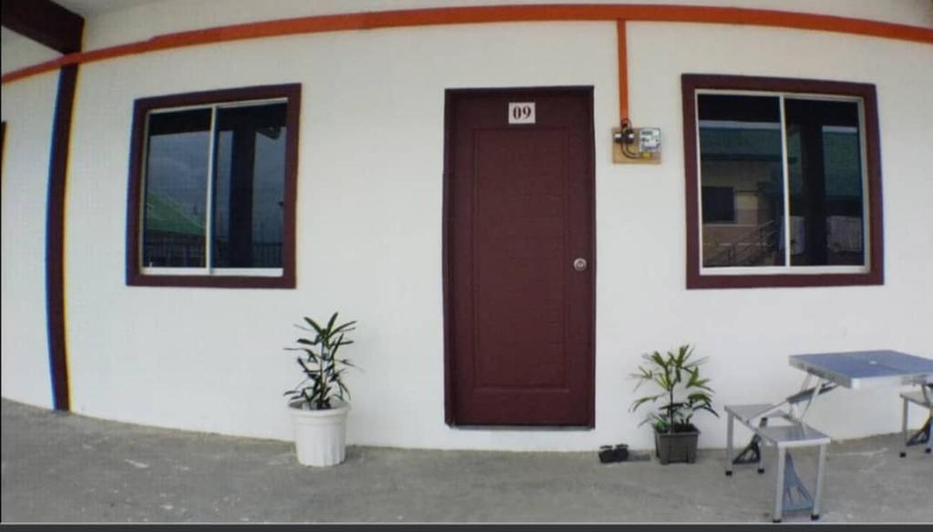 ein Gebäude mit einer braunen Tür sowie einem Tisch und Stühlen in der Unterkunft Santai HomeStay Sipitang in Sipitang