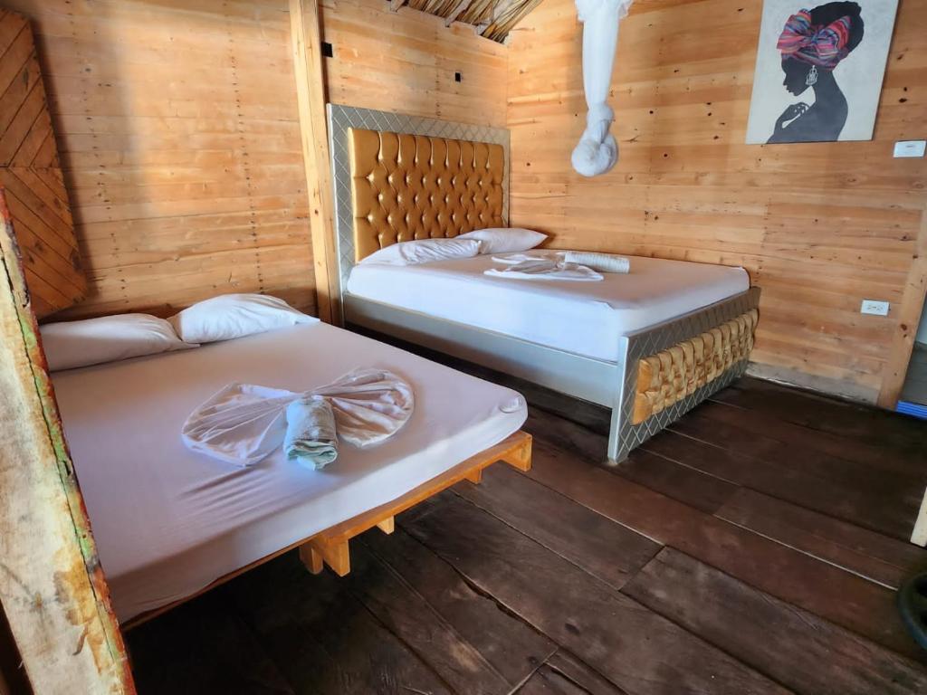 2 camas en una habitación con paredes de madera en Palos Locos Baru en Cartagena de Indias