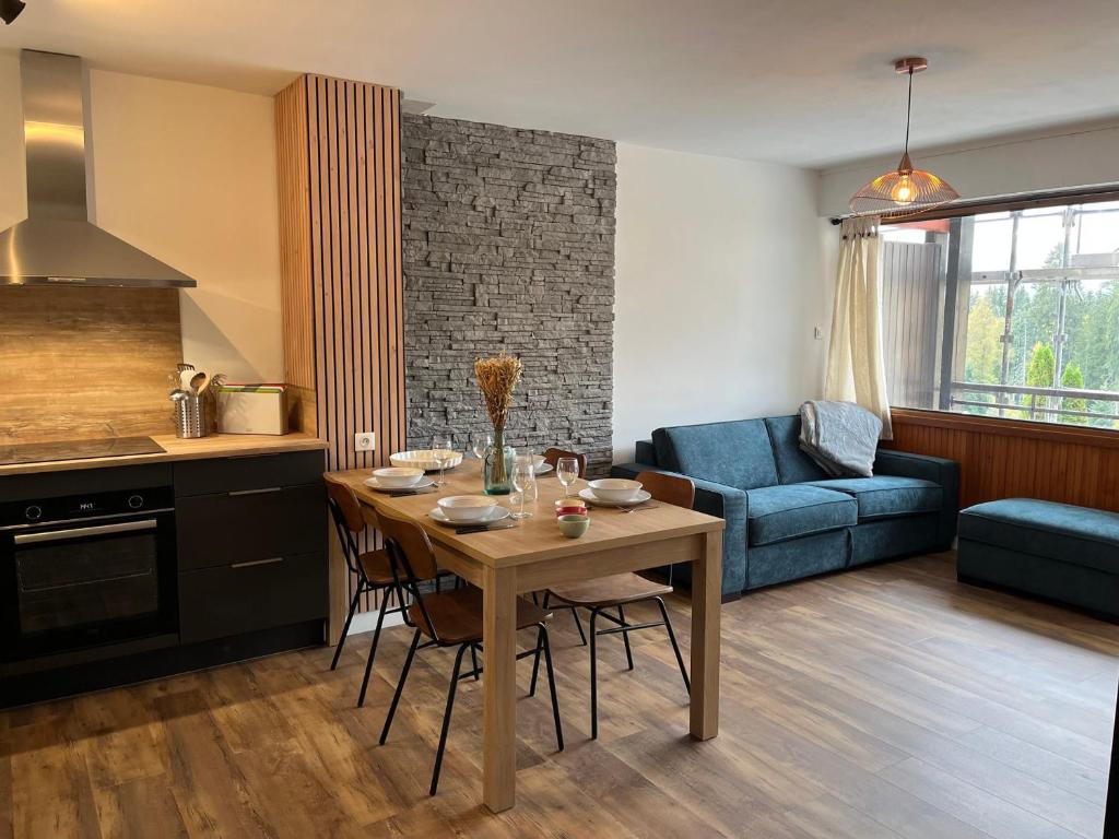 Il comprend une cuisine et un salon avec une table et un canapé bleu. dans l'établissement Superbe appartement rénové aux Gets, proche centre et pistes, balcon, casier à skis - FR-1-623-155, aux Gets
