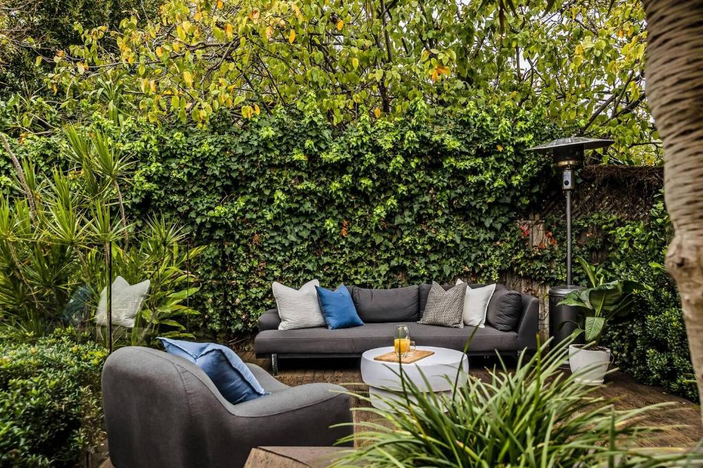 un giardino con divani e tavolo di fronte ad una siepe di Eastside Oasis Norwood a Kensington and Norwood