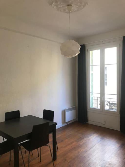 une salle à manger avec une table et des chaises noires dans l'établissement Charmant 2 pièces centre ville Nice, à Nice