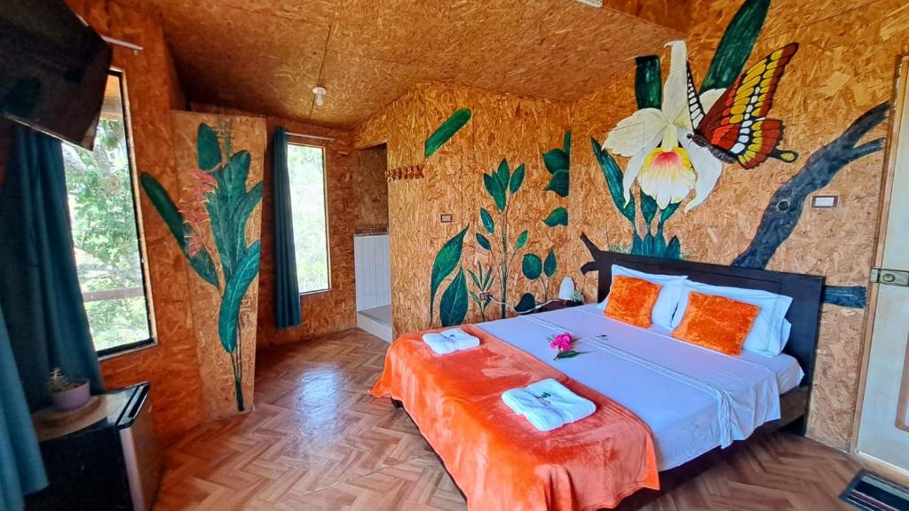a bedroom with a bed with a flower on the wall at Shapingo Wasi Eco Lodge in Moyobamba