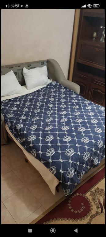 a bed with a blue and white quilt on it at Sweet Home Center City in Chişinău