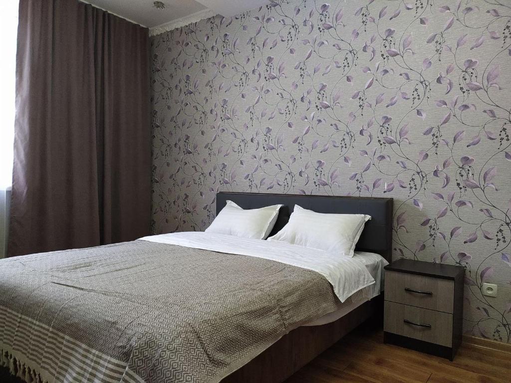 比什凱克的住宿－AURA on Isanov street 118，一间卧室配有一张带紫色花卉壁纸的床