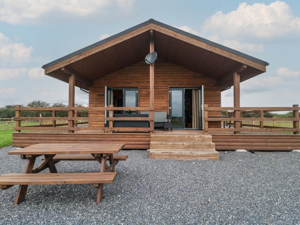 a log cabin with a picnic table and benches at The Lodge at Crossroads Farm in Bridgwater
