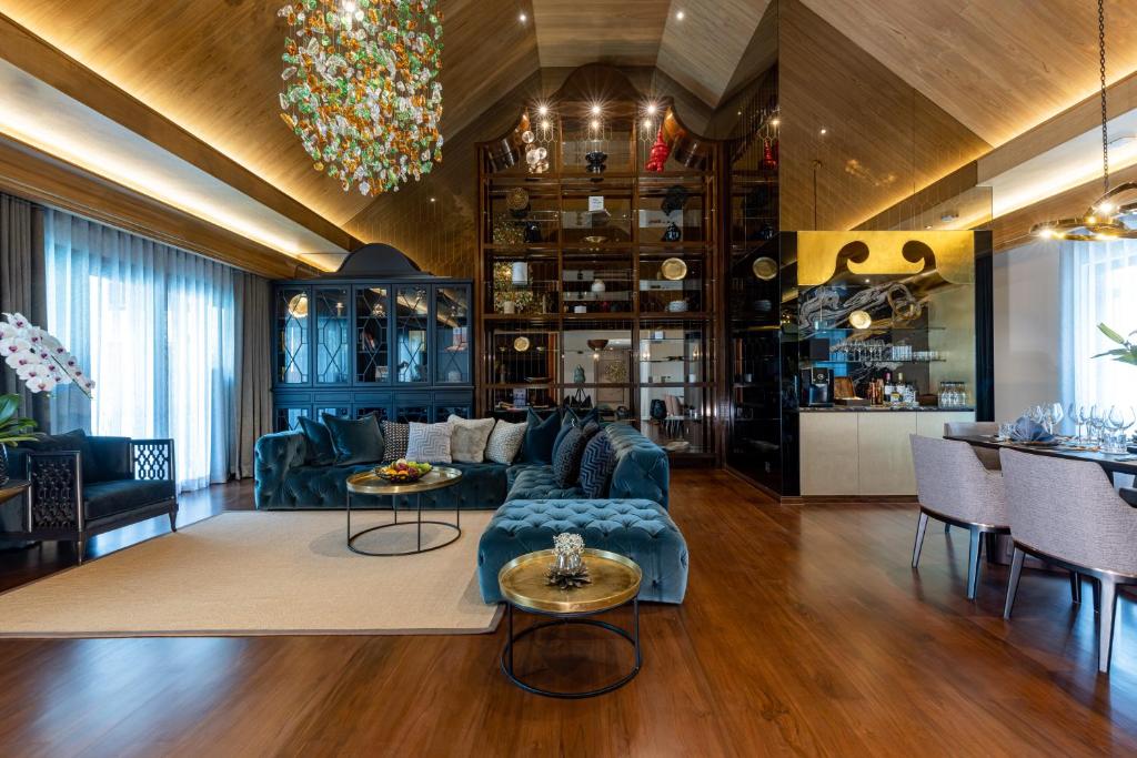 An intimate hotel lounge with a deep blue sectional, drinks cabinet and adjoining dining area.