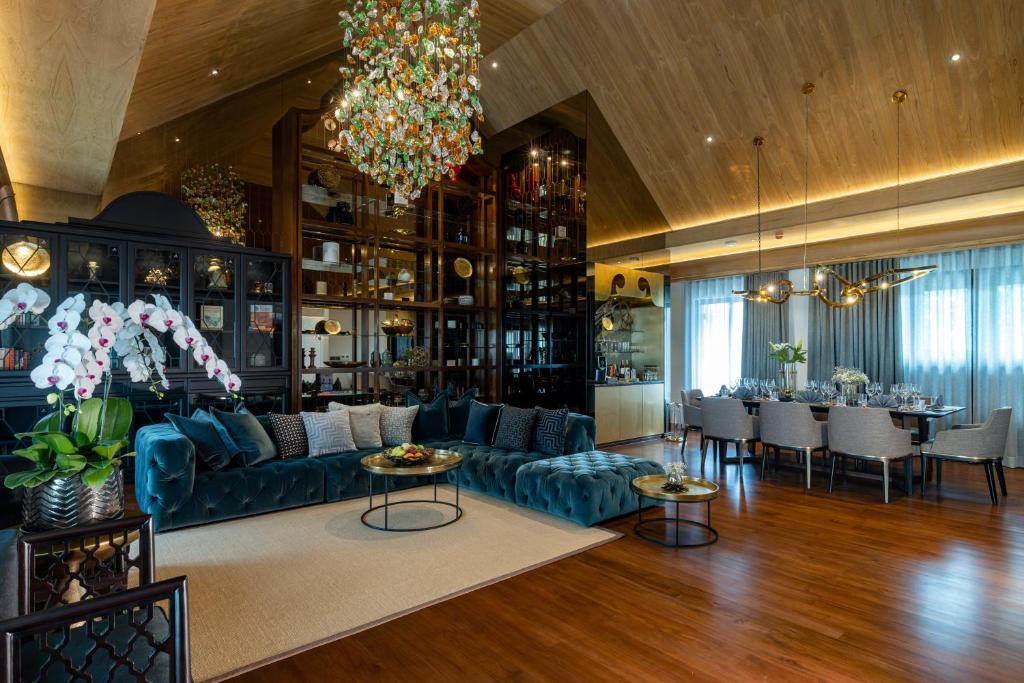 A richly furnished lounge and dining room arranged around a blue sectional sofa.
