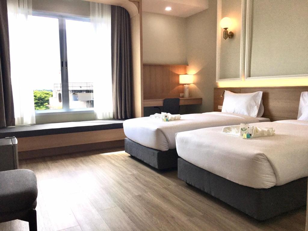 Cette chambre comprend 2 lits et une fenêtre. dans l'établissement Mayflower Grande Suite Hotel, à Phitsanulok