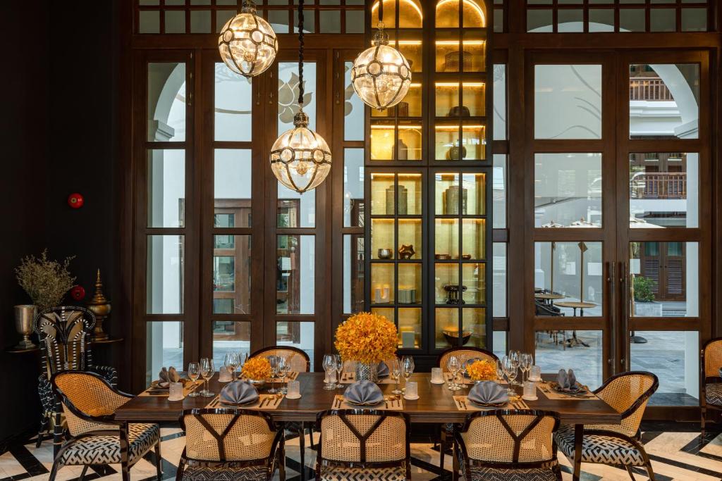 A formally set dining room beside tall windows and illuminated display shelves.