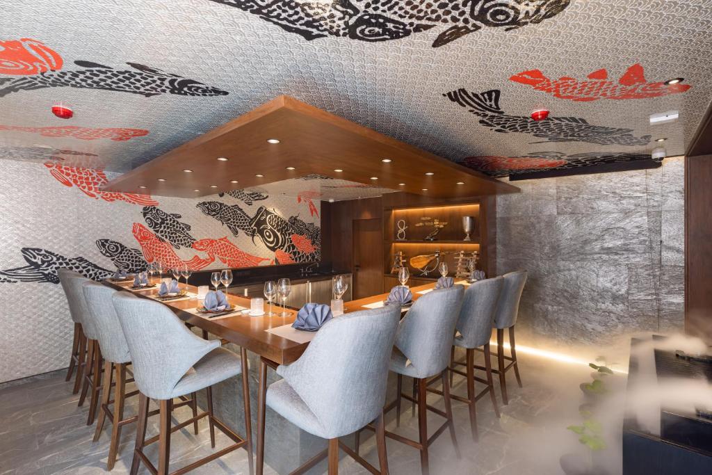 A long dining room wrapped in bold fish-patterned wall and ceiling artwork.