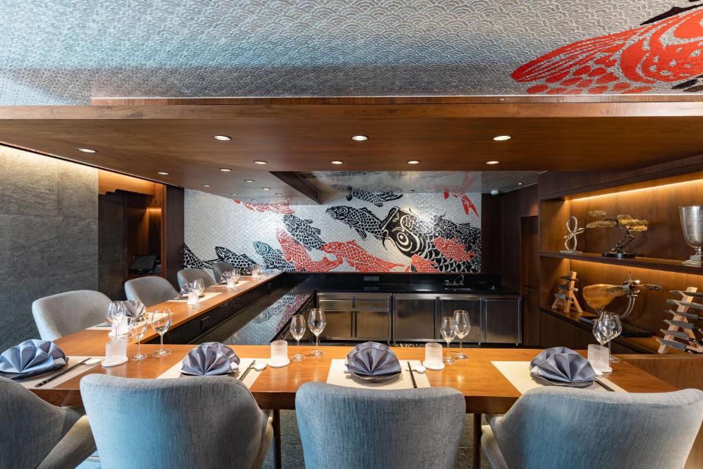 A compact private-style dining room with a long prepared table and fish artwork.