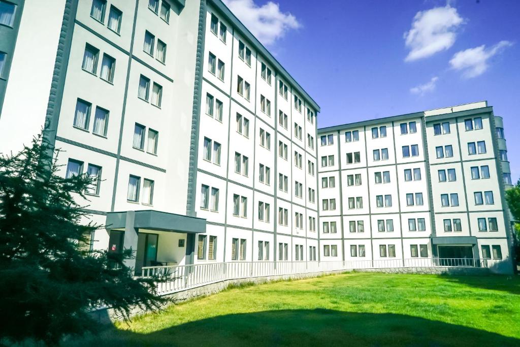 a large white building with a grass yard in front of it at Kumru Suites in Sarıcaeli