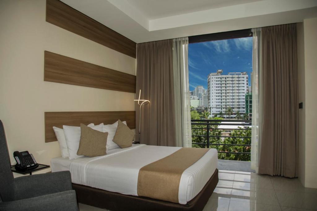 a bedroom with a bed and a window with a view at Eastland Hotel And Residences in Cebu City