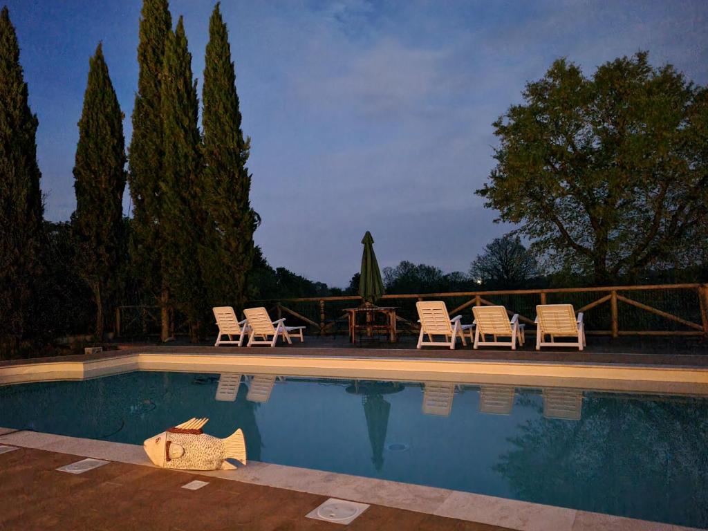 una piscina con sillas, una mesa y una mesa con sillas en Fornace del Conte, en Abbadia di Montepulciano