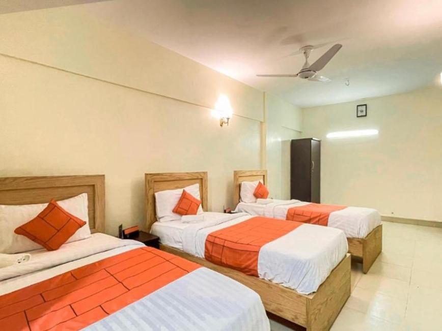 1 dormitorio con 2 camas con sábanas de color naranja y blanco en Hotel Rooms DHA en Karachi