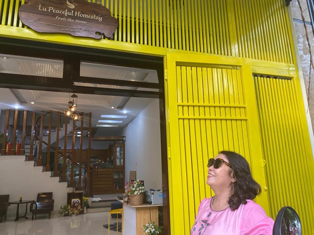 Una donna in piedi davanti a un muro giallo di Lu Peaceful Homestay a Da Nang