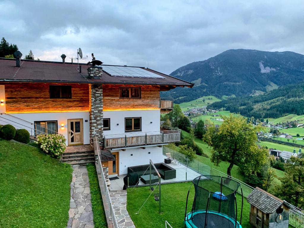 une maison sur une colline avec un court de tennis dans l'établissement Apartment Oberguggenhausen, à Brixen im Thale