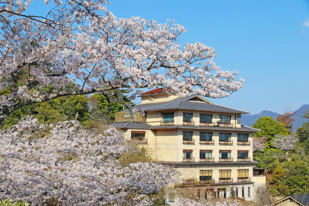 un gran edificio con árboles akuraakura delante de él en Jukeiso, en Miyajima