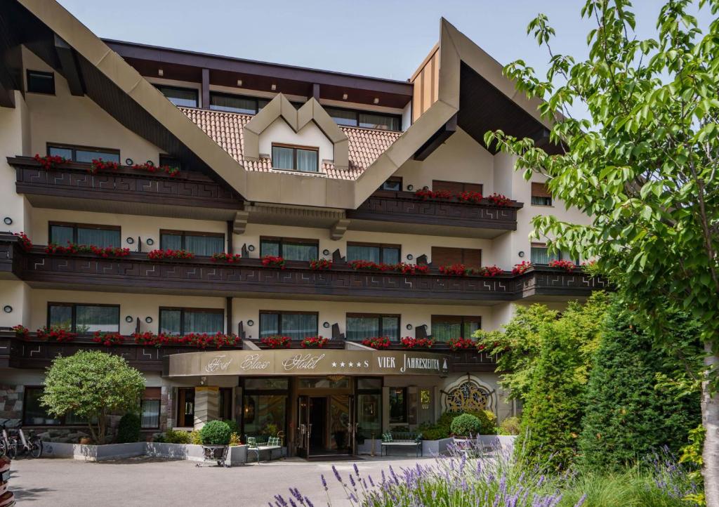 ein Hotel mit einem großen Gebäude mit Blumen darauf in der Unterkunft Hotel Vier Jahreszeiten in Schlanders
