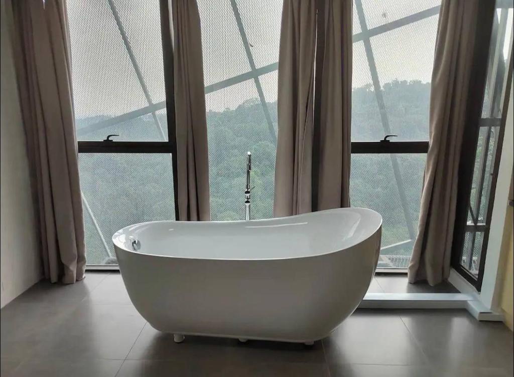 eine Badewanne vor einem großen Fenster in der Unterkunft Bathtub Soho, Forest View Empire Damansara in Petaling Jaya