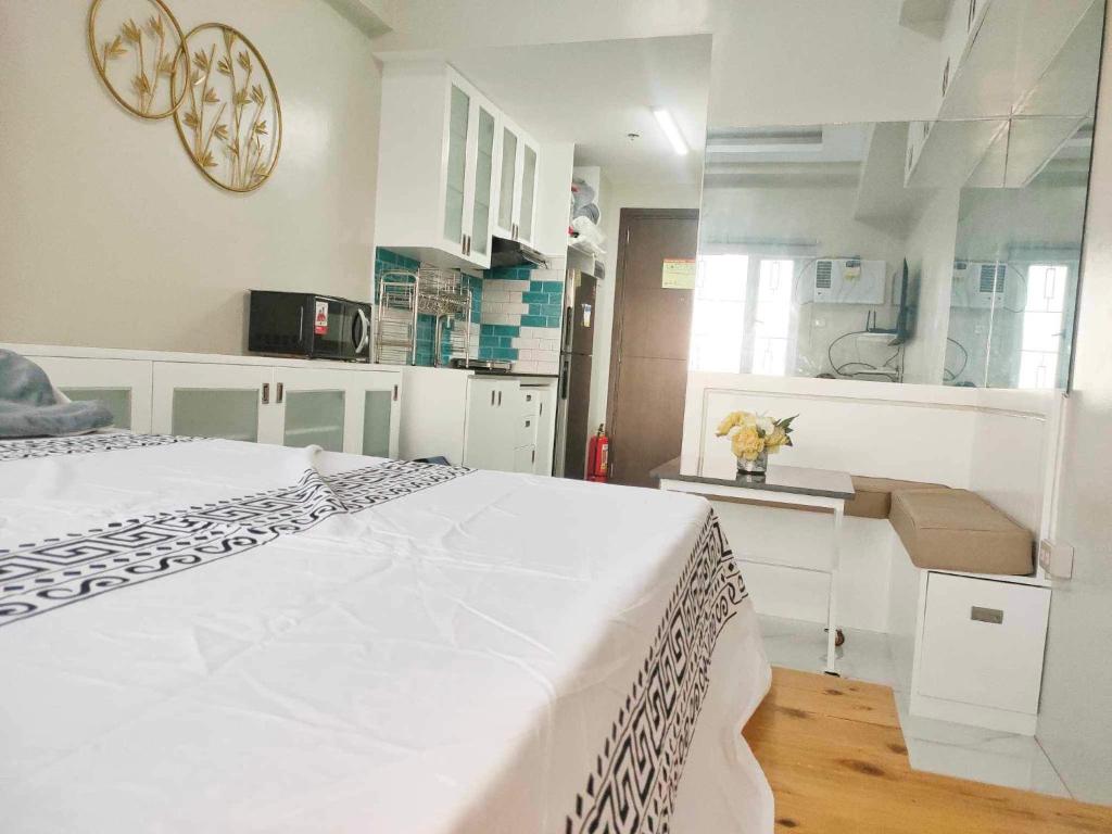 a white bedroom with a bed and a kitchen at Best Condo Studio within Limketkai Center in Cagayan de Oro